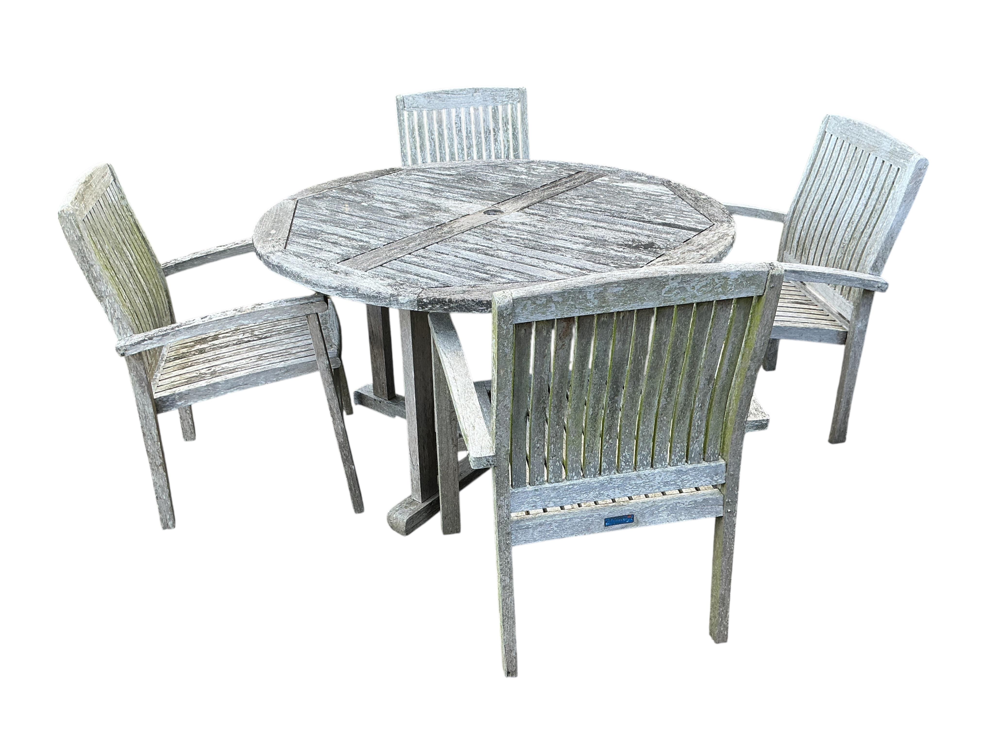 A Lindsey circular weathered teak garden table, diameter 130cm and four chairs